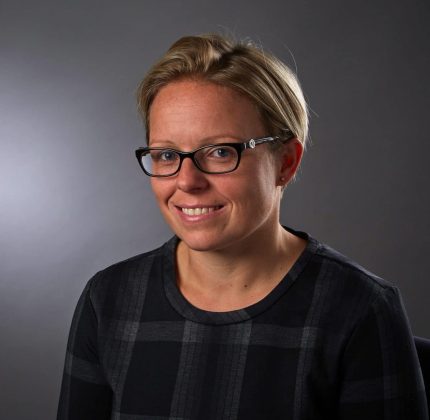 new partner Tara Crisp headshot of woman with short hair and glasses