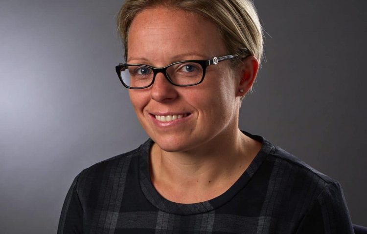 new partner Tara Crisp headshot of woman with short hair and glasses