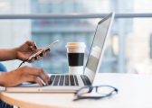 Image of person flexible working on laptop on table with coffee and glasses