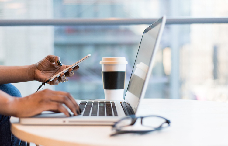 Image of person flexible working on laptop on table with coffee and glasses