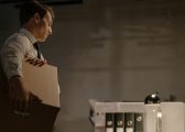 white man holding cardboard box staring at desk following unfair dismissal