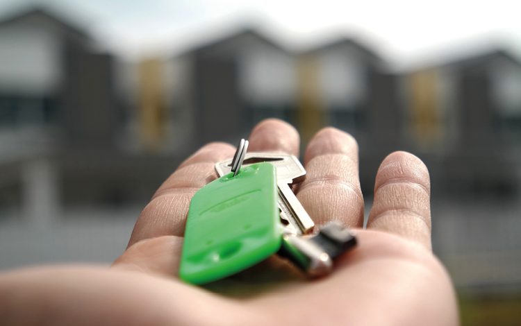 Picture of hand with house keys on green keyring for Conveyancing process blog