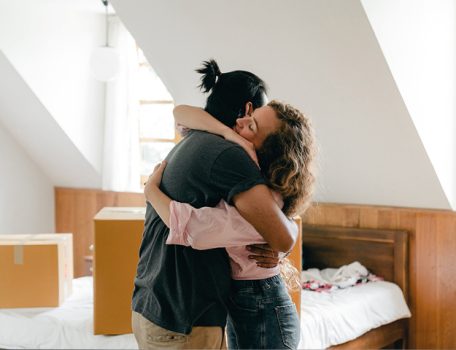 Cohabitation Law Image of couple hugging surrounded by packing boxes in new home
