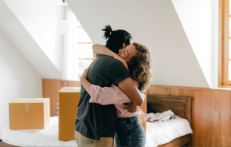 Cohabitation Law Image of couple hugging surrounded by packing boxes in new home