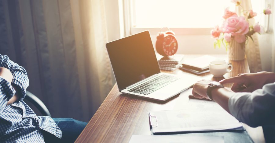 Image of two men across a desk one pointing to his watch to suggest lateness and absenteeism