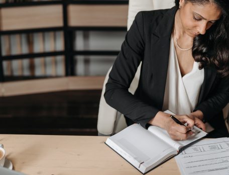 Persistent Absence Blog image showing a professional woman at at desk writing in a notepad