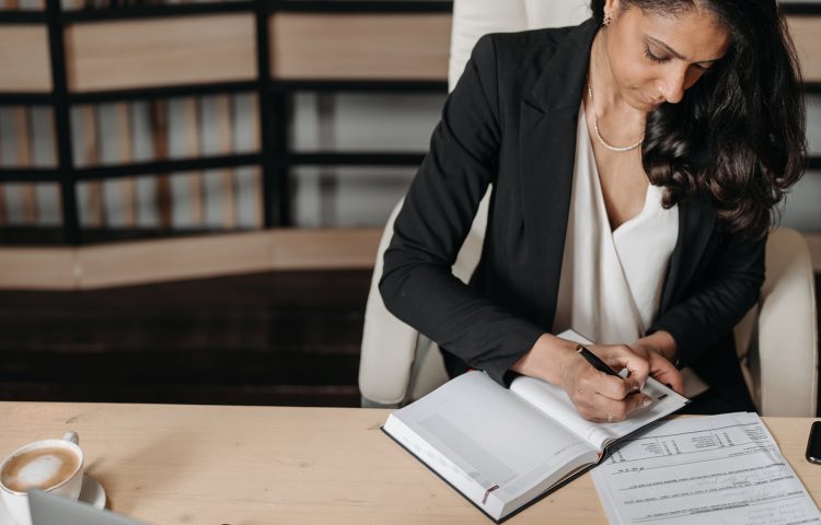 Persistent Absence Blog image showing a professional woman at at desk writing in a notepad