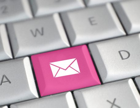 Image of computer keyboard with one key replaced in pink by an envelope icon representing an email signature