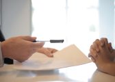 Image of two people sitting at a table signing a piece of paper for a Settlement Agreement