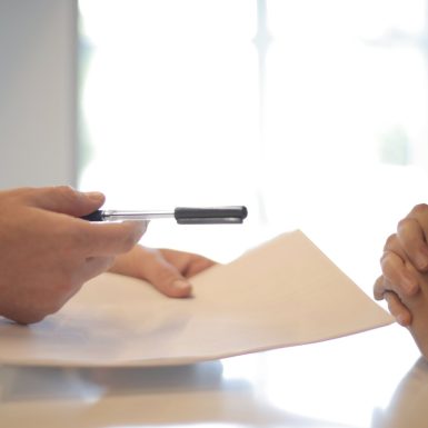 Image of two people sitting at a table signing a piece of paper for a Settlement Agreement