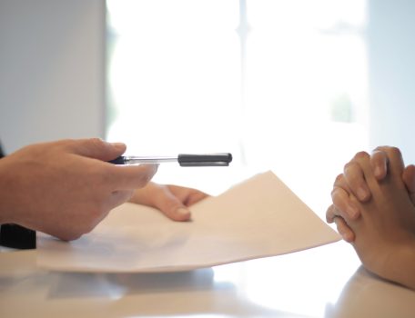 Image of two people sitting at a table signing a piece of paper for a Settlement Agreement