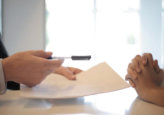 Image of two people sitting at a table signing a piece of paper for a Settlement Agreement