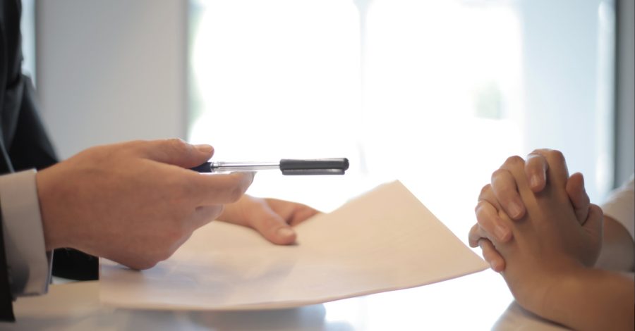 Image of two people sitting at a table signing a piece of paper for a Settlement Agreement