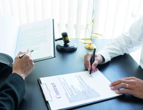 law, libra scale and hammer on the table, 2 men are dealing and signing commercial contract, law matters determination