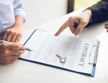 image of two peoples hands, one pointing at a contract on a clipboard and the other poised to sign it for the Hibberts Blog The Landlord and Tenant Act 1954 - Review and Consultation
