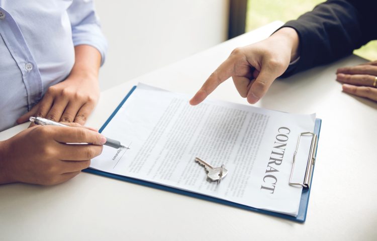 image of two peoples hands, one pointing at a contract on a clipboard and the other poised to sign it for the Hibberts Blog The Landlord and Tenant Act 1954 - Review and Consultation