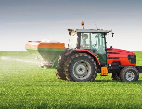 Image of a red tractor on a spraying a green field for the Inheritance Tax Blog