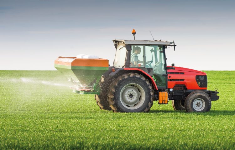 Image of a red tractor on a spraying a green field for the Inheritance Tax Blog